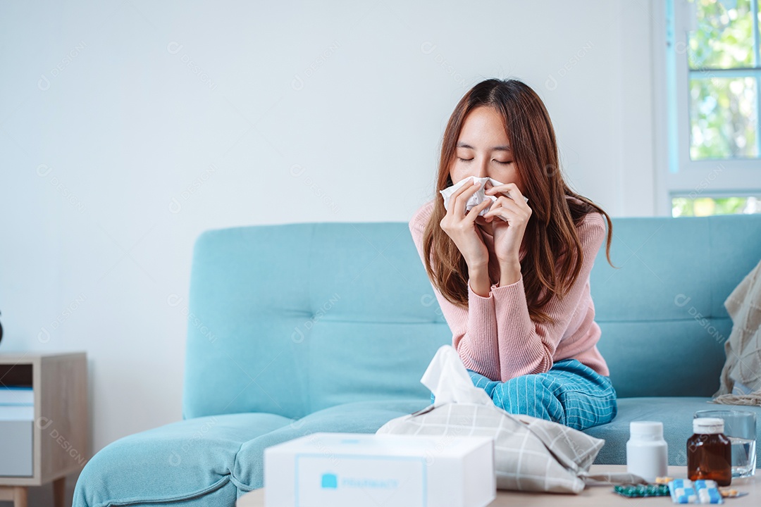 Paciente jovem asiática doente com frio ela espirra com lenço de papel no sofá