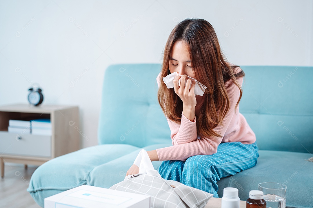 Paciente jovem asiática doente com frio ela espirra com lenço de papel no sofá