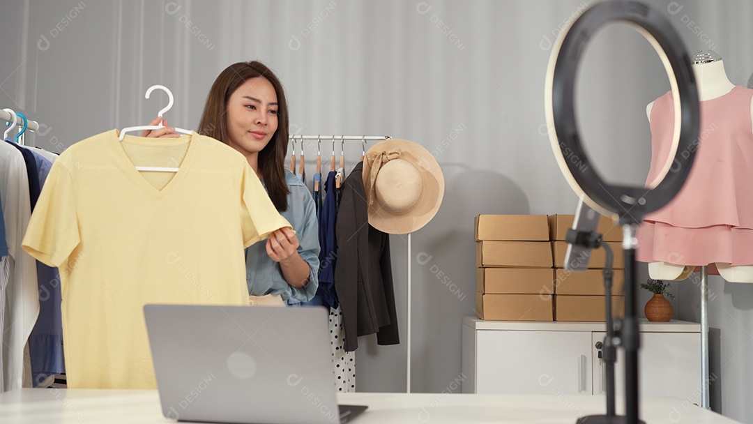 Jovem asiática usa telefone inteligente e fala ao vivo, vende roupas da moda online.