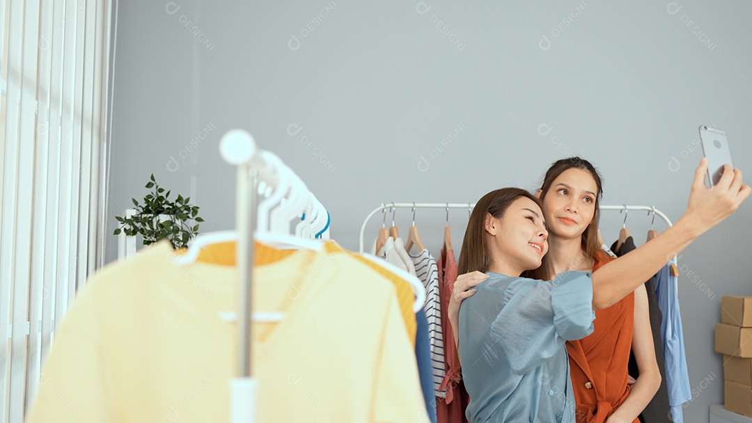 Jovem asiática usa telefone inteligente e fala ao vivo, vende roupas da moda online.