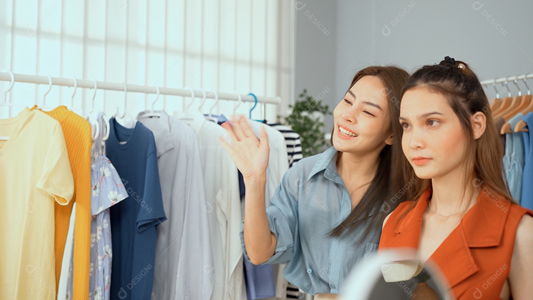 Jovem asiática usa telefone inteligente e fala ao vivo, vende roupas da moda online.