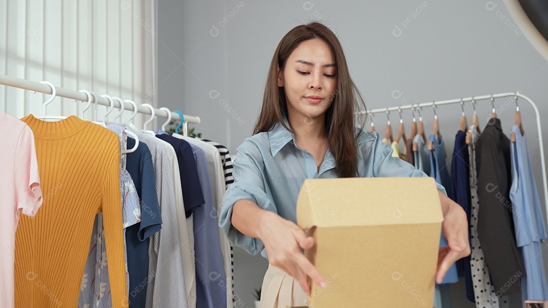 Jovem asiática usa telefone inteligente e fala ao vivo, vende roupas da moda online.