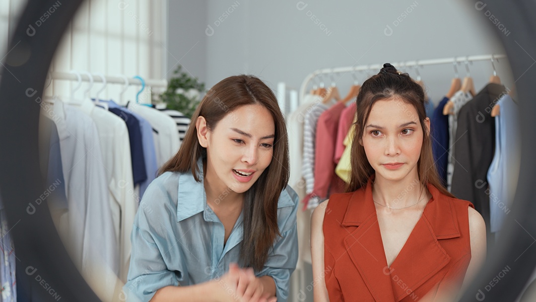 Jovem asiática usa telefone inteligente e fala ao vivo, vende roupas da moda online.