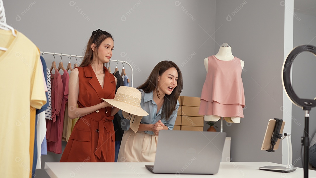 Jovem asiática usa telefone inteligente e fala ao vivo, vende roupas da moda online.