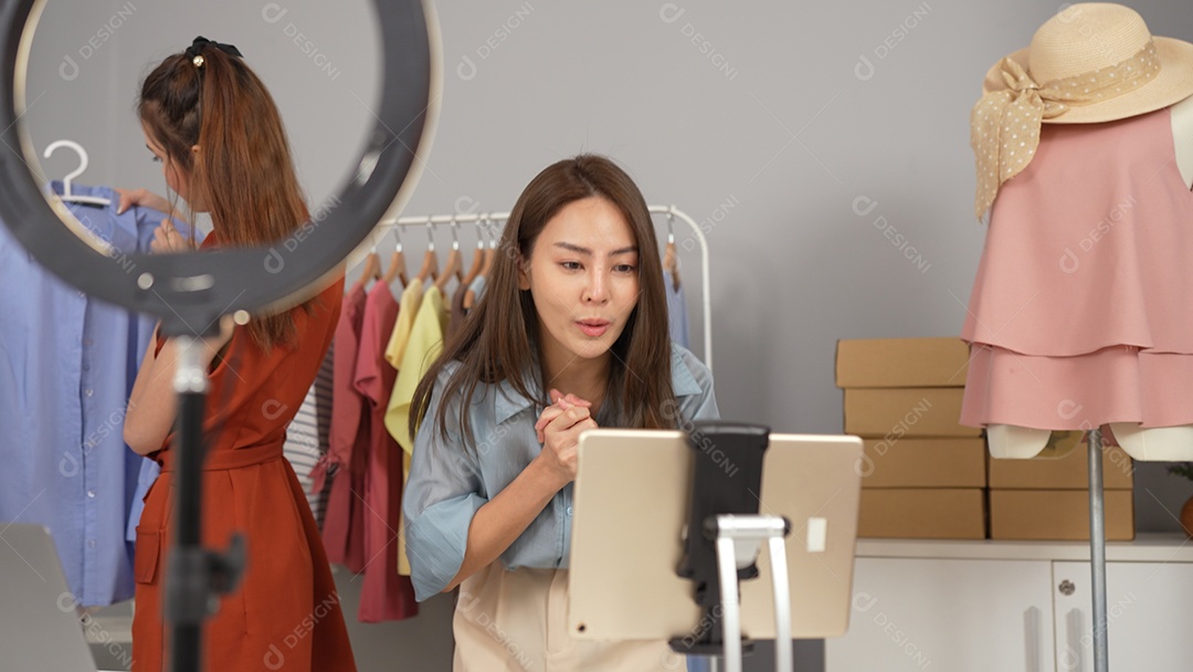 Jovem asiática usa telefone inteligente e fala ao vivo, vende roupas da moda online.