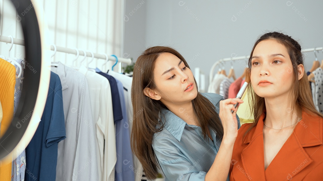 Blogueira asiática se maquiando on-line via câmera social.