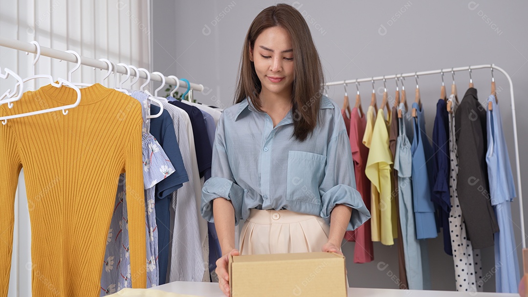 Proprietária jovem asiática de site de compras on-line preparando o pedido para o cliente.