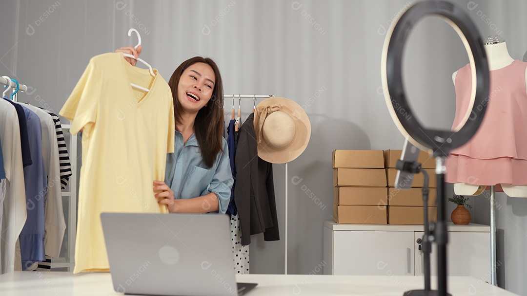 Jovem blogueira asiática escolhe roupas no trilho de roupas.