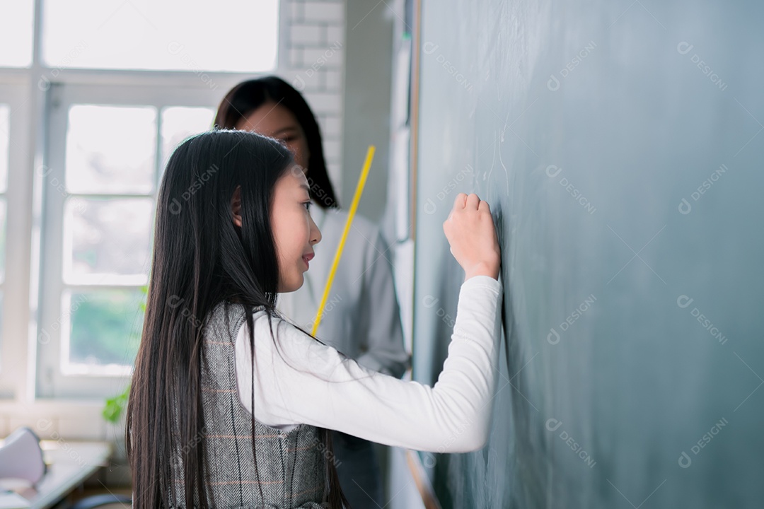 Mulher sorridente de professora asiática ensinando aluno em sala de aula
