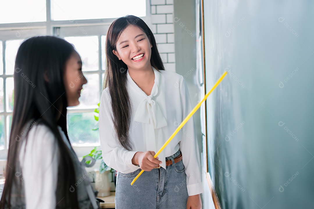 Mulher sorridente de professora asiática ensinando aluno em sala de aula
