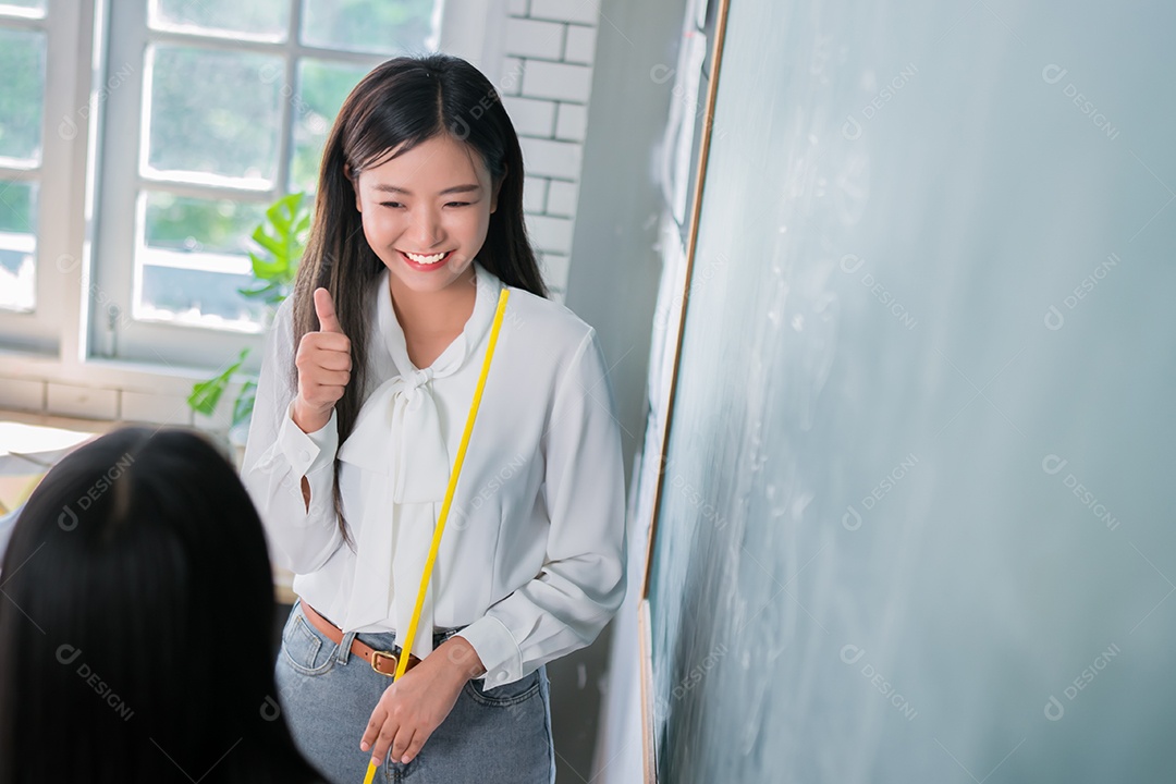 Mulher sorridente de professora asiática ensinando aluno em sala de aula