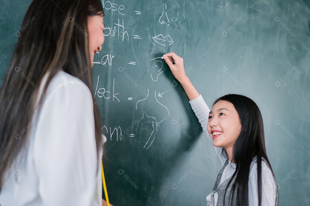 Mulher sorridente de professora asiática ensinando aluno em sala de aula
