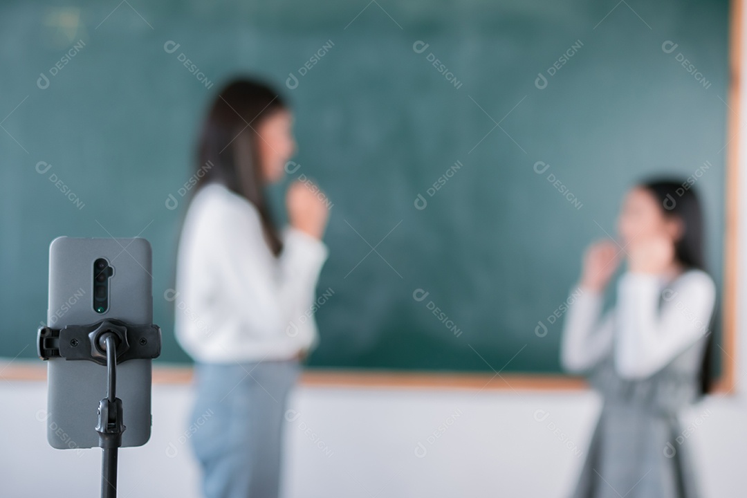 Mulher sorridente de professora asiática ensinando aluno em sala de aula