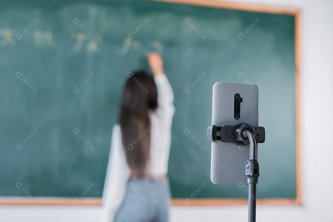 Mulher sorridente de professora asiática ensinando aluno em sala de aula