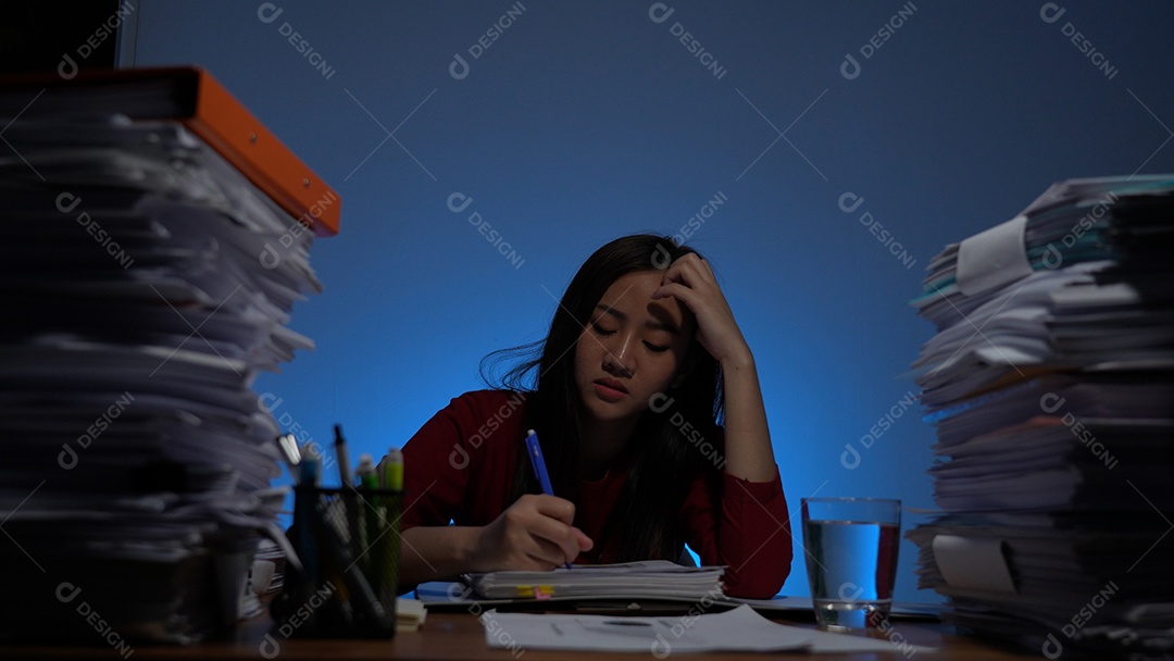 Estressada jovem asiática sentada trabalhando horas extras fazendo negócios tardios no escritório à noite