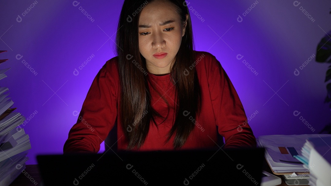 Estressada jovem asiática sentada trabalhando horas extras fazendo negócios tardios no escritório à noite