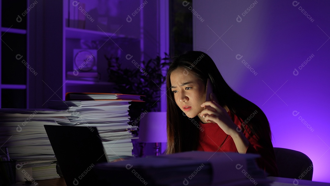 Estressada jovem asiática sentada trabalhando horas extras fazendo negócios tardios no escritório à noite