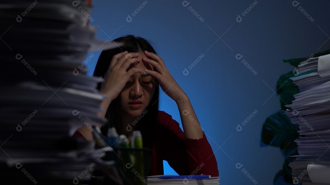 Estressada jovem asiática sentada trabalhando horas extras fazendo negócios tardios no escritório à noite