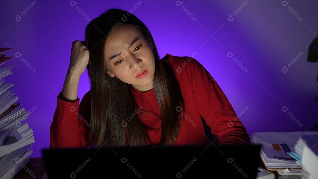 Jovem asiática sentada trabalhando horas extras fazendo negócios tardios no escritório à noite
