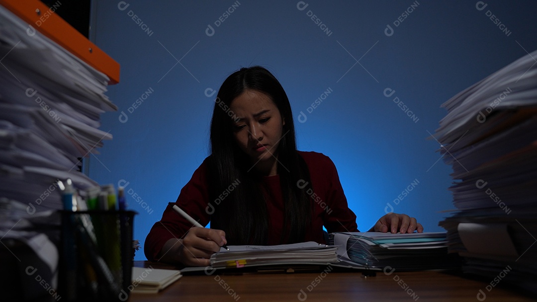 Jovem asiática sentada trabalhando horas extras fazendo negócios tardios no escritório à noite