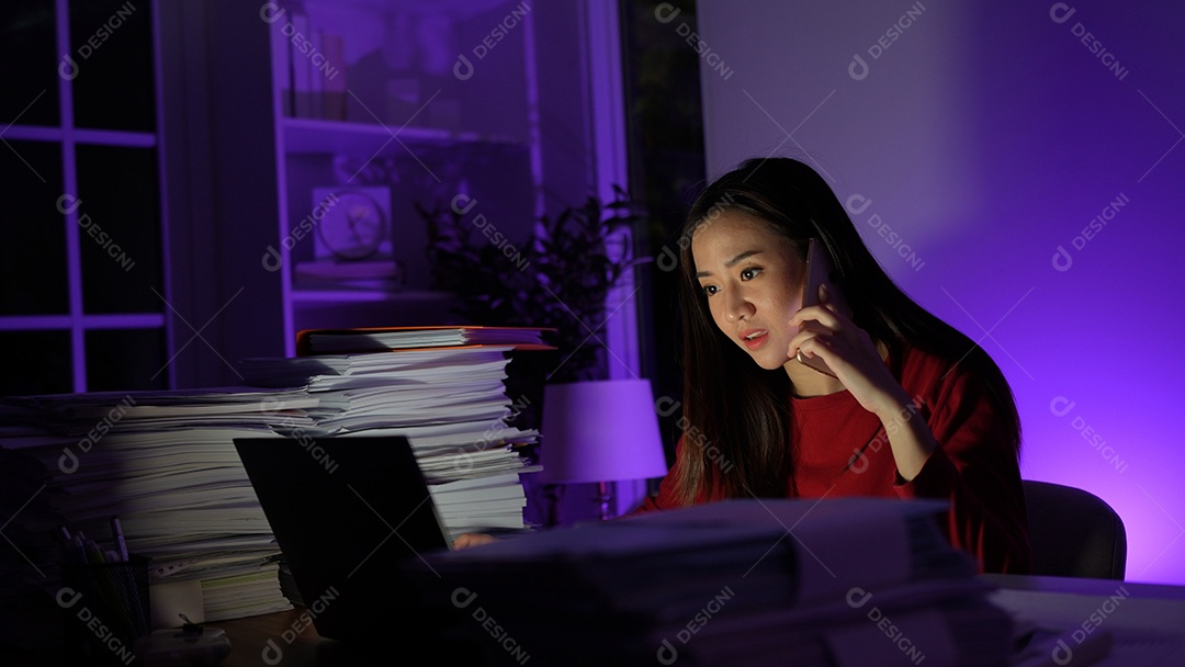 Jovem asiática sentada trabalhando horas extras fazendo negócios tardios no escritório à noite