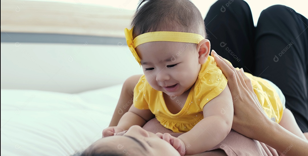 Mãe asiática com seu bebê recém-nascido na cama de manhã