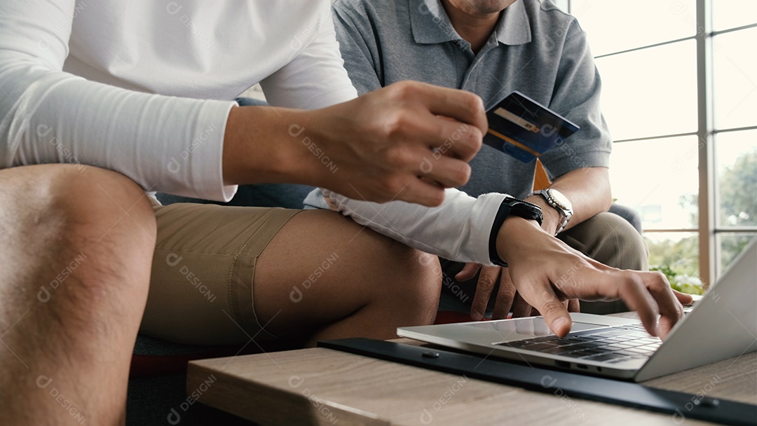 O pai sênior asiático e o filho adulto passam tempo juntos com o laptop em casa.