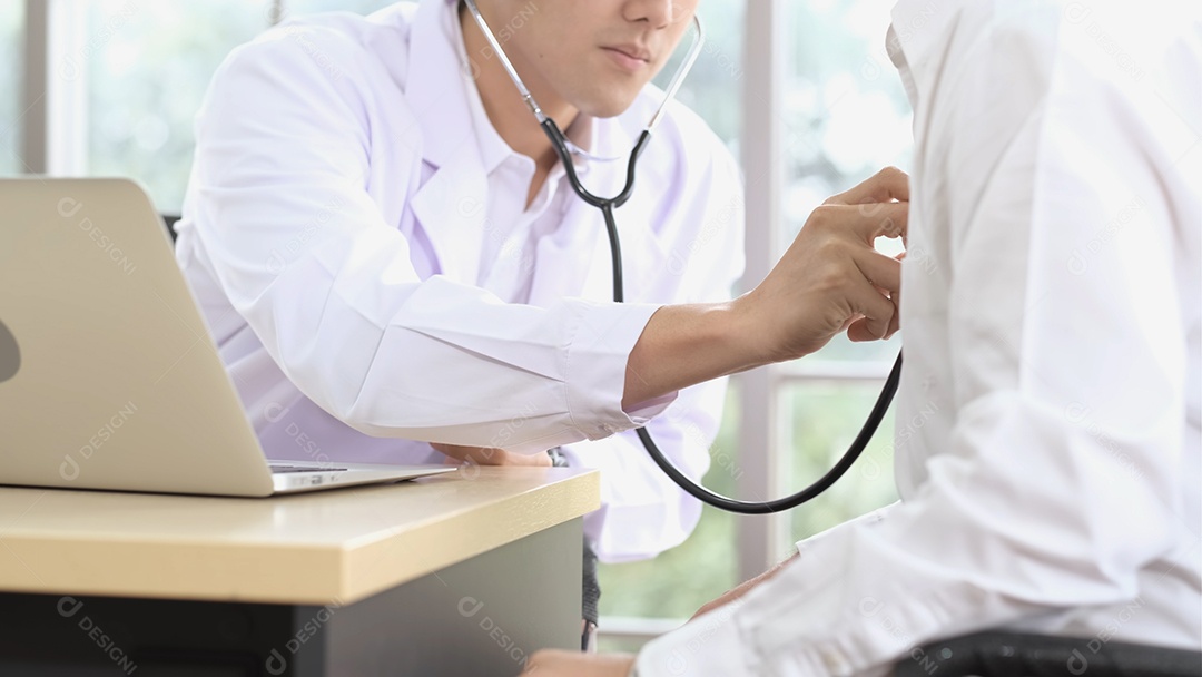 Médico masculino asiático usa estetoscópio para examinar batimentos cardíacos de pacientes idosos.