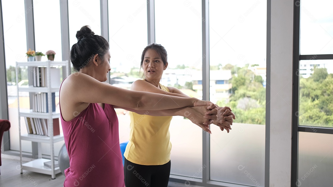 A jovem mulher asiática está relaxando na prática de alongamento de poses de ioga em pé com seu personal trainer.