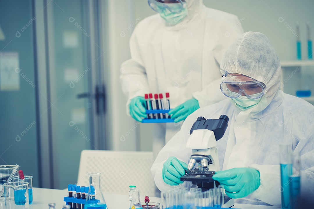 Grupo de cientistas com um microscópio em laboratório, desenvolvendo uma vacina.