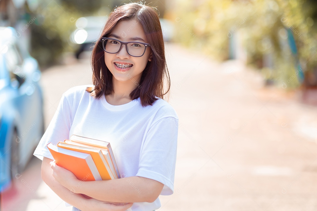 O retrato da mulher asiática estudante com aparelho dental segurando livros
