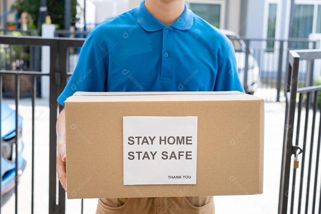 O serviço de entrega masculino de uniforme fornece um pacote de caixa de papelão para o cliente receptor na frente de casa