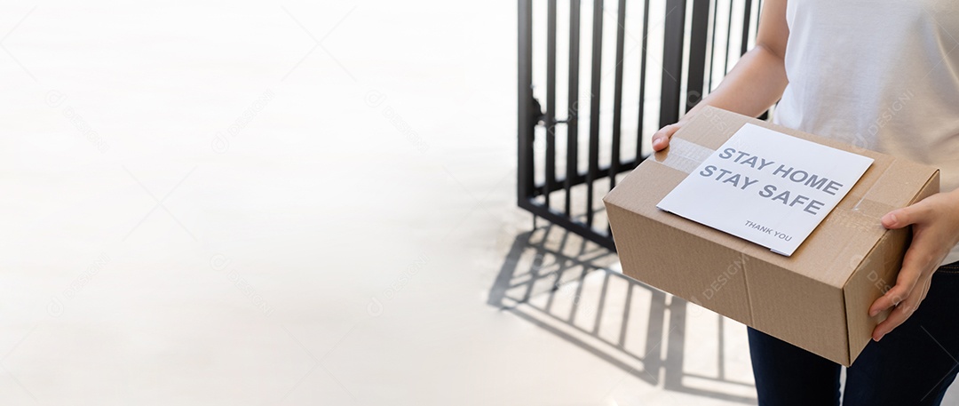 O serviço de entrega masculino de uniforme fornece um pacote de caixa de papelão para o cliente receptor na frente de casa