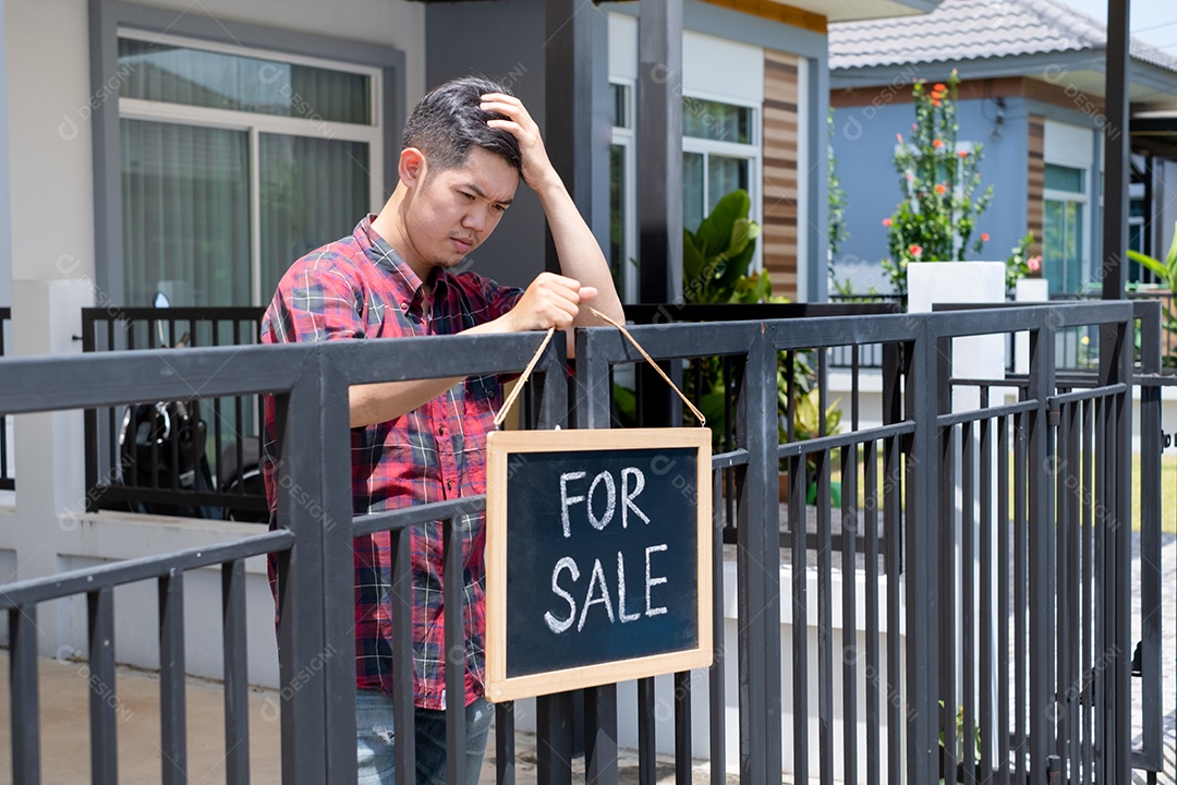 Homem colocando placa de venda de casa