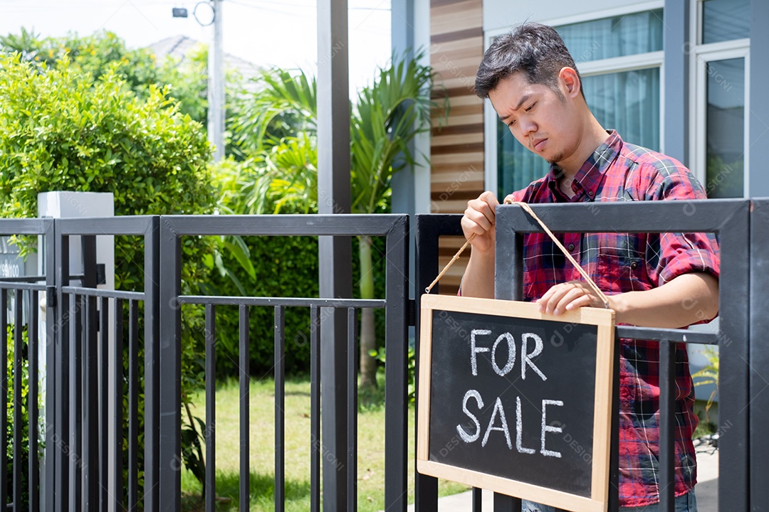 Homem com placa de venda da casa