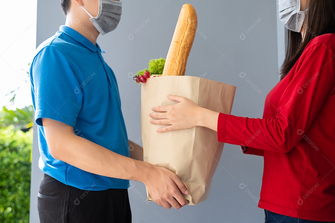 O entregador de comida usando máscara dá supermercado de compras de frutas e vegetais para a casa da frente do cliente