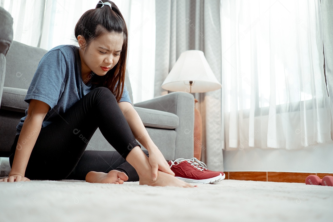 Após o treino da jovem mulher asiática sentada, tire os sapatos apertados