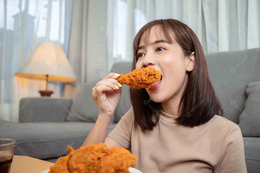 Jovem mulher asiática comendo frango frito desfrutando do serviço de entrega de fast food