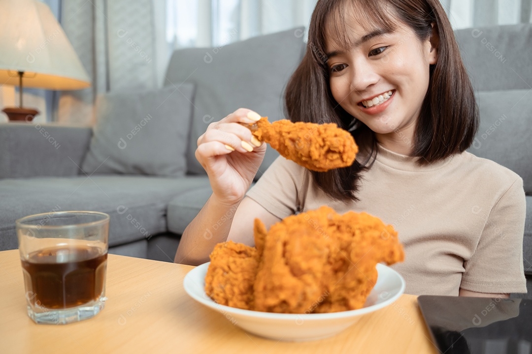 Jovem mulher asiática comendo frango frito desfrutando do serviço de entrega de fast food