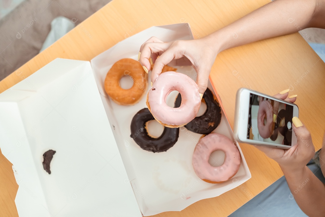 Jovem mulher asiática comendo rosquinha na sala de estar