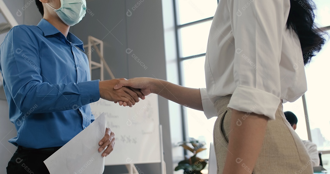 A visão aproximada de um homem e uma mulher asiáticos de negócios apertando as mãos chegaram