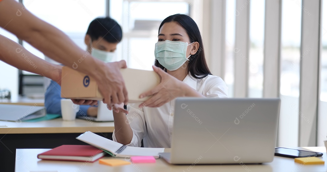 Jovem empresária asiática com máscara recebendo um pacote do correio