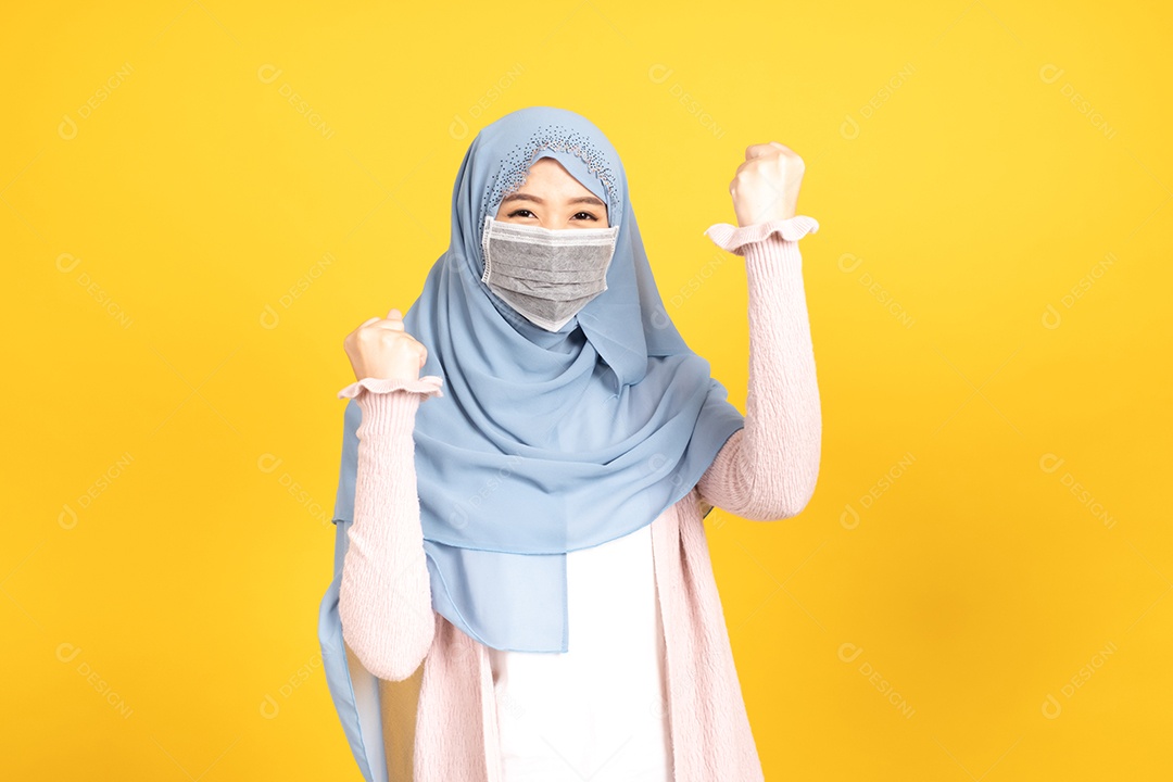 Retrato de menina muçulmana asiática em hijab usando máscara facial no estúdio amarelo.