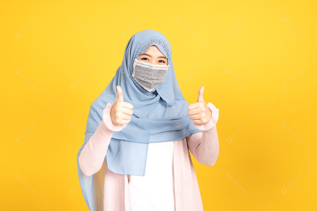 Retrato de menina muçulmana asiática em hijab usando máscara facia em fundo amarelo