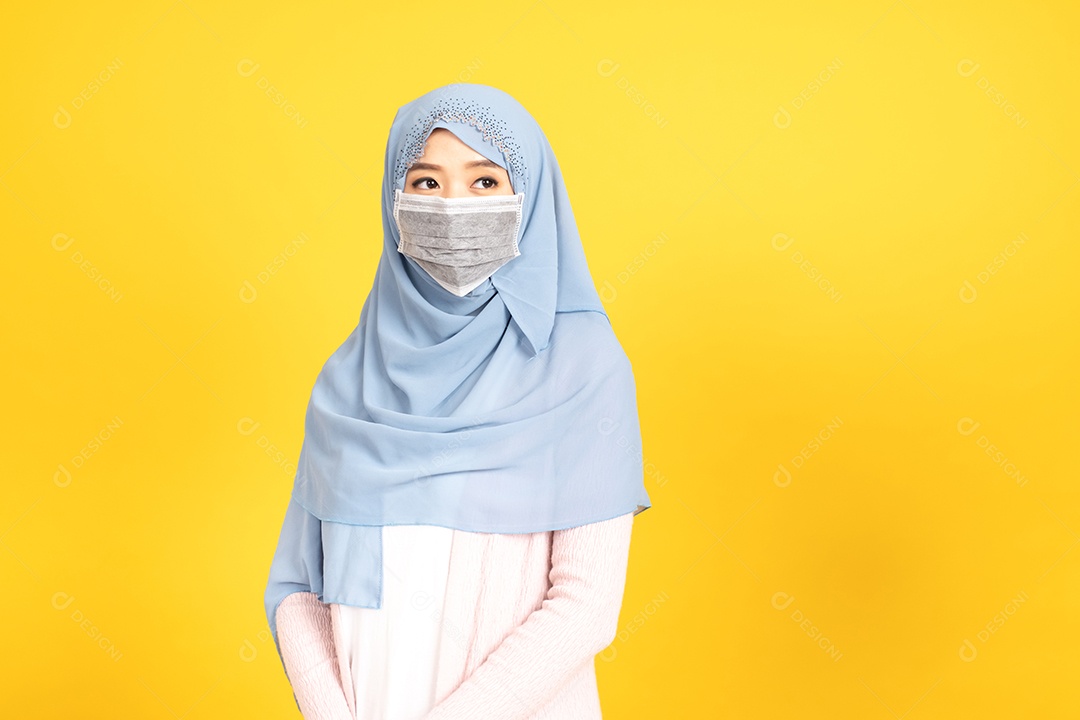 Retrato de menina muçulmana asiática em hijab usando máscara facia em fundo amarelo