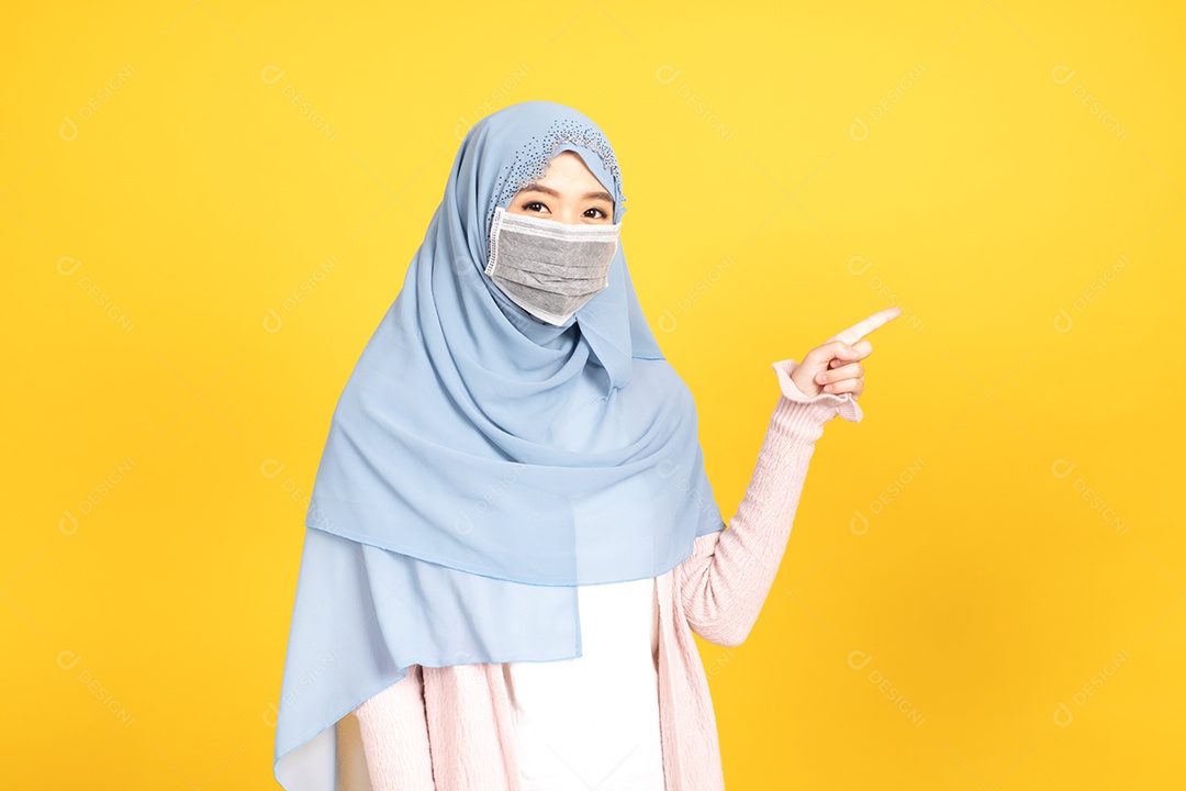 Retrato de menina muçulmana asiática em hijab usando máscara facia em fundo amarelo