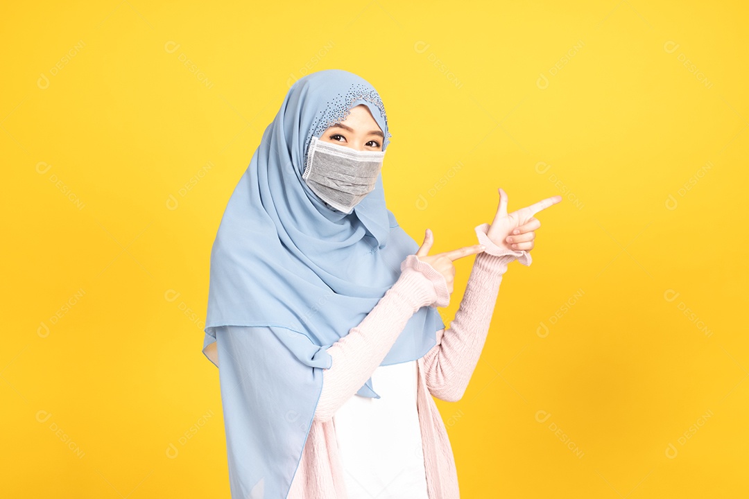 Retrato de menina muçulmana asiática em hijab usando máscara facia em fundo amarelo