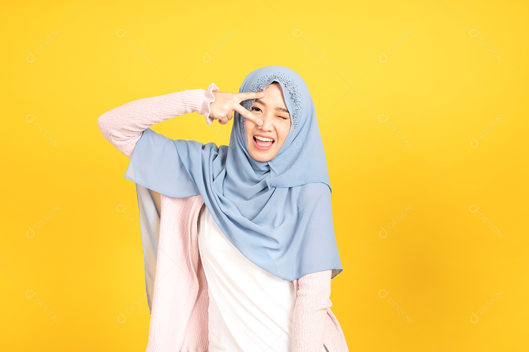 Retrato da menina muçulmana asiática no hijab em fundo amarelo