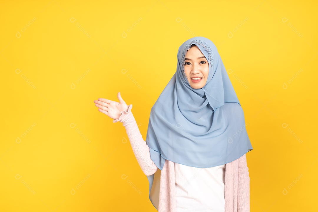 Retrato de menina muçulmana asiática em hijab apontando as mãos de lado.