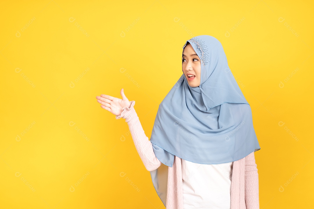 Retrato de menina muçulmana asiática em hijab apontando as mãos de lado.